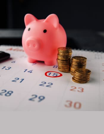 Piggy bank and coins on a calendar